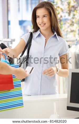 Woman purchasing clothes in shop, getting back credit card, smiling at shop assistant.?