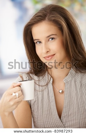 Happy woman drinking coffee, holding cup, smiling at camera.?