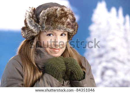 Young attractive woman dressed up warm in coat, fur-hat and gloves, enjoying winter, smiling.?