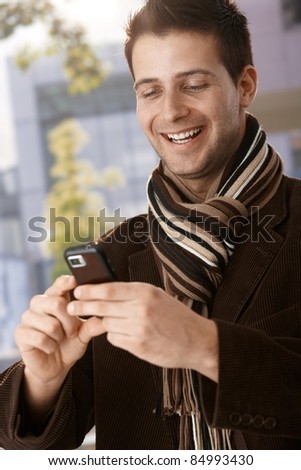 stock-photo-happy-guy-wearing-scarf-looking-at-mobile-phone-handheld-laughing-84993430.jpg