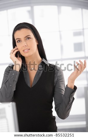 Attractive woman speaking on mobile phone, looking up, gesturing,?