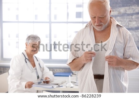 stock photo Mature male patient undressing at doctor's room