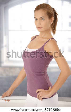 Young woman standing at ballet bar in ballet posture, looking at camera.?