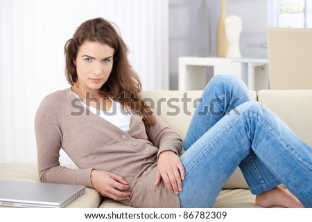 Beautiful young woman laying on sofa, wearing jeans.?