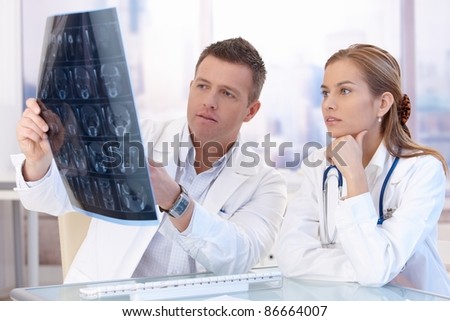 Two doctors studying x-ray image, consulting in bright office.?