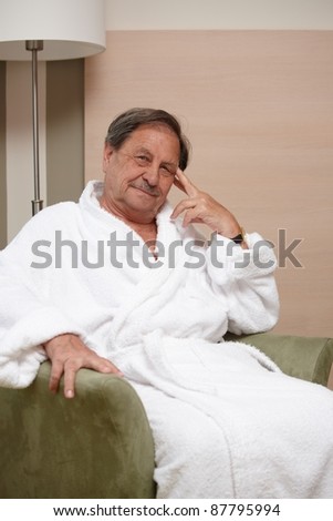 Happy elderly man sitting in armchair, looking at camera.?