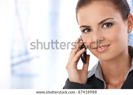 Portrait of attractive young female on phone call, smiling, looking at camera.?