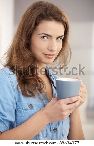 Portrait of young beautiful woman drinking tea, smiling.?