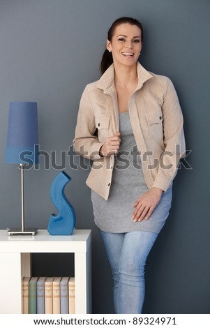 Happy woman standing posing in stylish living room, looking at camera.?