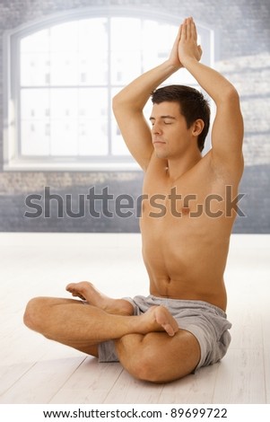 Handsome sporty guy doing yoga meditation in lotus posture with eyes closed.?