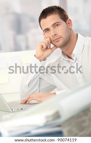 Troubled businessman sitting at desk in office.?