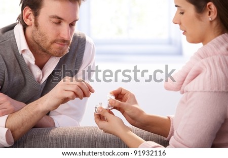 Handsome young man proposing to woman at home, giving engagement ring.?