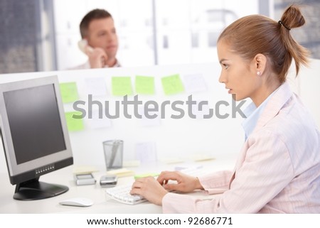 Young woman sitting at desk, working on computer, busy.?