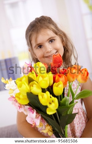 Cute little girl holding bouquet of flowers, smiling on mother\'s day, looking at camera.?