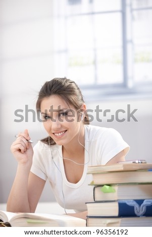 Pretty college student laying on floor, listening music, studying, smiling.?