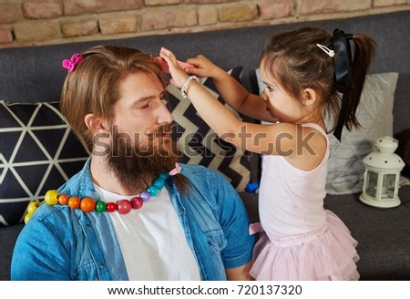 Father and little daughter playing at home, styling hair.