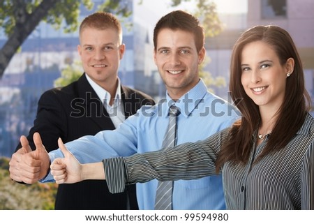 Happy and successful business team giving thumb up, outdoor portrait.