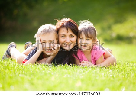 Happy family outdoors on the grass in a park, smiling faces all lying down having fun