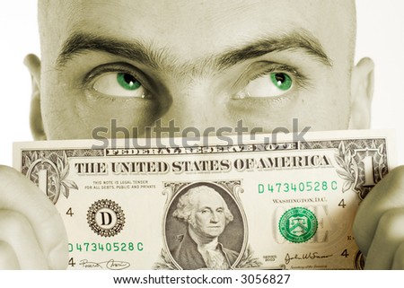 A man holds a US one dollar bill to his face obsesessed with a fantasy of more money. The color of his eyes has been changed to match the green color in the dollar bill.