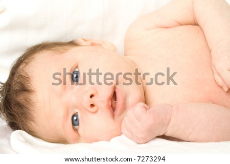 Newborn Caucasian baby girl laying on her back, with her face turned toward the camera.