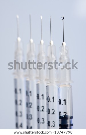 Five syringes with injection needles on blue background.