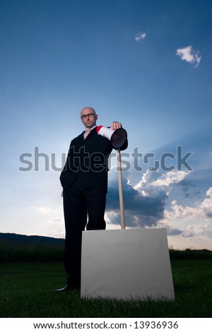 Serious bold man in glasses and black suit, holding poster and megaphone. Space for text is available.
