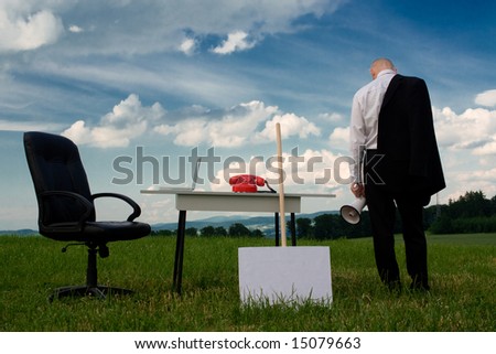 A business man outside in a field with a desk and chair.