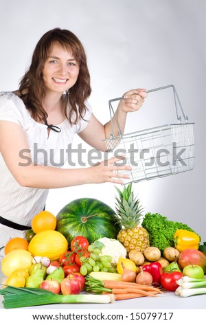 Woman with an empty grocery basket and an assortment of fruits and vegetables.
