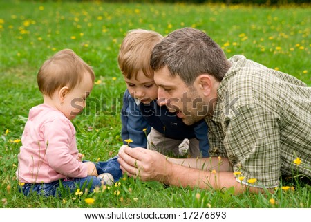 Happy family of father, baby girl and small son, playing together in the garden.