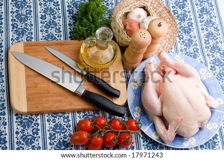 Raw chicken, other ingredients and tools arranged on table to prepare a chicken delicacy.
