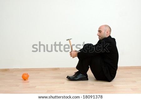Man holding hammer looking at an orange piggy bank.