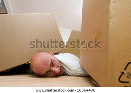 Portrait of head of man with body trapped under cardboard boxes.