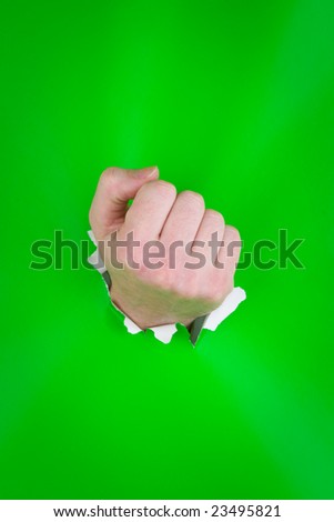 Close up of clenched fist having punched through green background.
