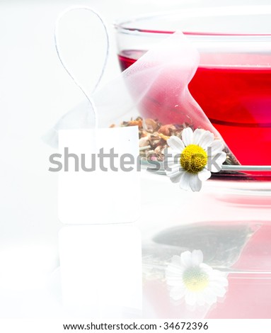 Cup of tea with a white chamomile flower and an herbal tea bag.  Isolated against a white background.