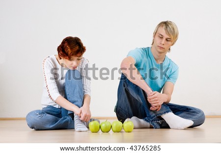 Man and woman sitting with four apples.