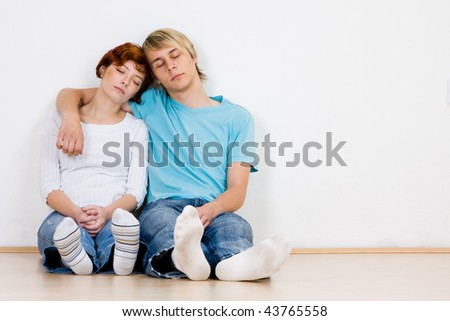Closeup of affectionate young couple sleeping against wall indoors.