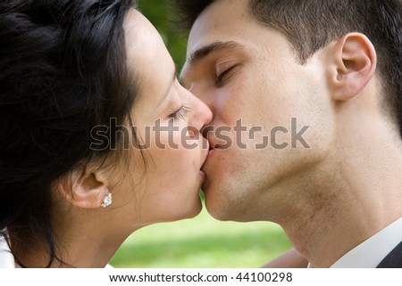 Closeup of a couple kissing over the shoulder of the man.
