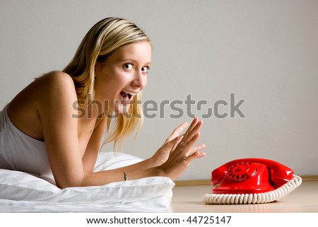 Excited girl laying on floor by a bright red dial telephone.