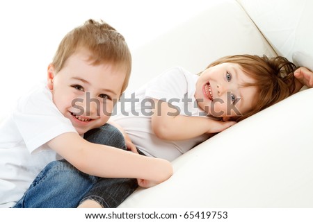 Happy preschool boy and baby sister relaxing on white background.