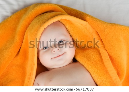 Portrait of smiling baby boy with towel covering head.