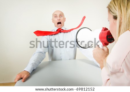A bullied male worker being blasted by the volume of his boss\'s megaphone.