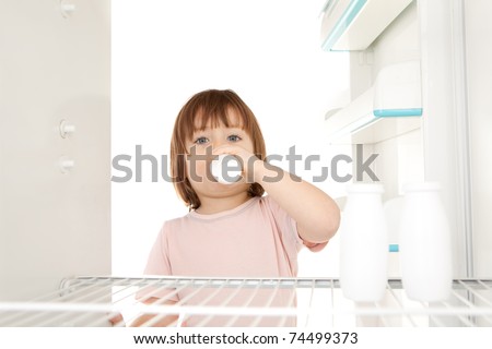 A young girl getting milk out of the refrigerator.