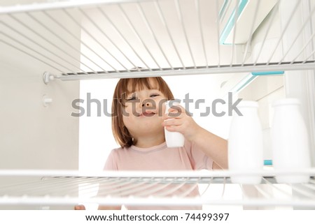 A young girl getting milk out of the refrigerator.