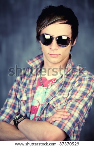 Half body portrait of handsome male teenager with sunglasses and check shirt; studio background.
