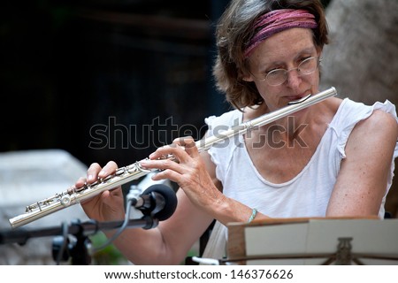 Senior woman is playing flute.