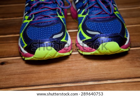 Pair of blue neon running shoes on a wooden floor background
