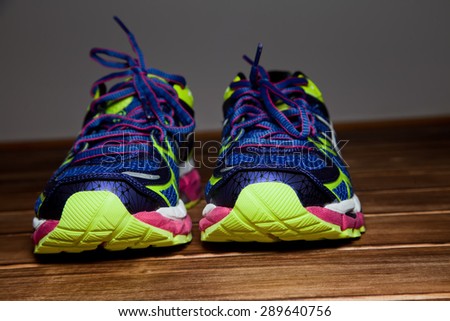 Pair of blue neon training shoes on a wooden floor background