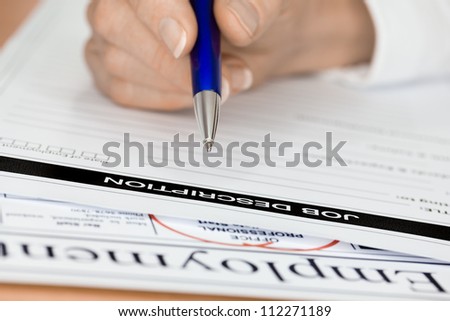 A hand with a pen writing job description (focus on pen nib and job description words)