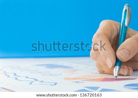 Hand with Pen Editing Graphs Blue background with copy space