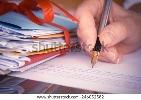Vintage or retro style Hand with pen writing a letter by mail tied with ribbon closeup